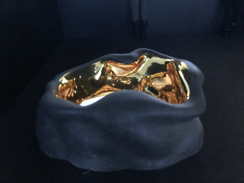 配合影像《金色之名》存在的裝置散落在屏幕周圍，屏幕嵌在雕塑里被安置在地面上
